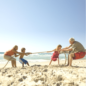 grandparents and their grandchildren on a beach playing tug-of-war.