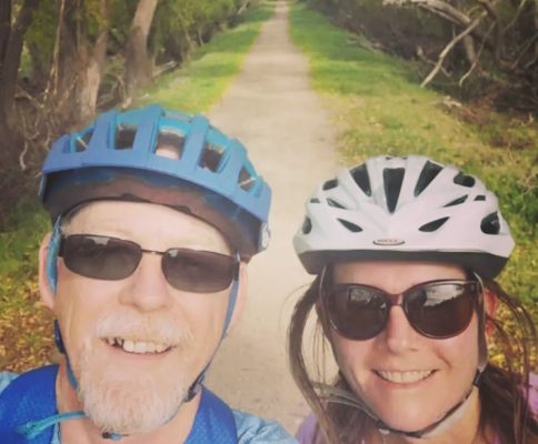 a man and a woman wearing helmets on a path.