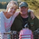 kathy and malcolm cane posing for a picture with their dog on a farm bike.