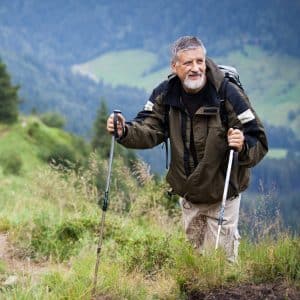 a man with a backpack and trek poles walking up a hill.