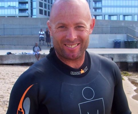 a man with a bald head wearing a wet suit.