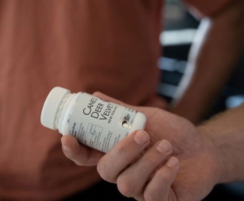 a man holding a bottle of canes deer velvet capsules in his hand.